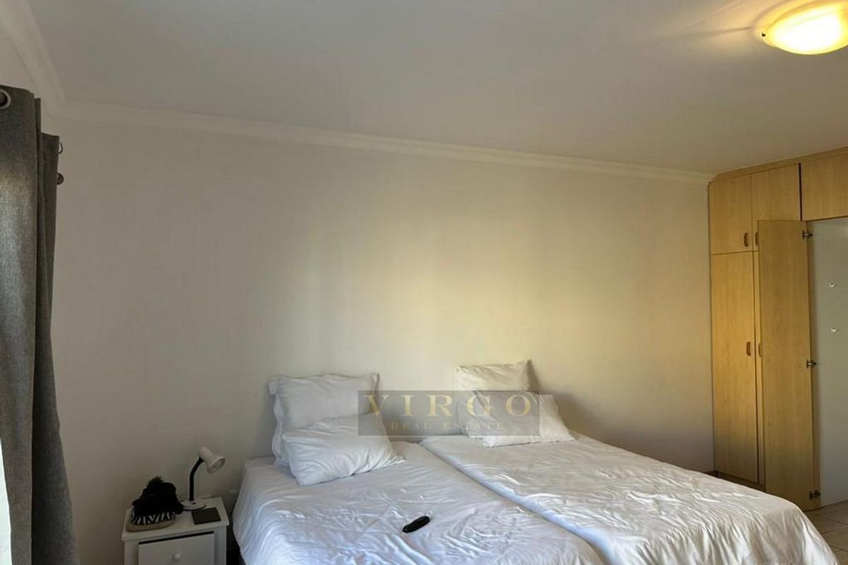 A bedroom featuring built-in wooden cupboards and neutral wall finishes, providing a functional and tidy sleeping space.