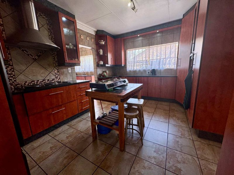 A functional kitchen featuring wood-finish cabinetry, granite countertops, tiled flooring, and a built-in extractor fan, offering a practical layout for daily cooking.