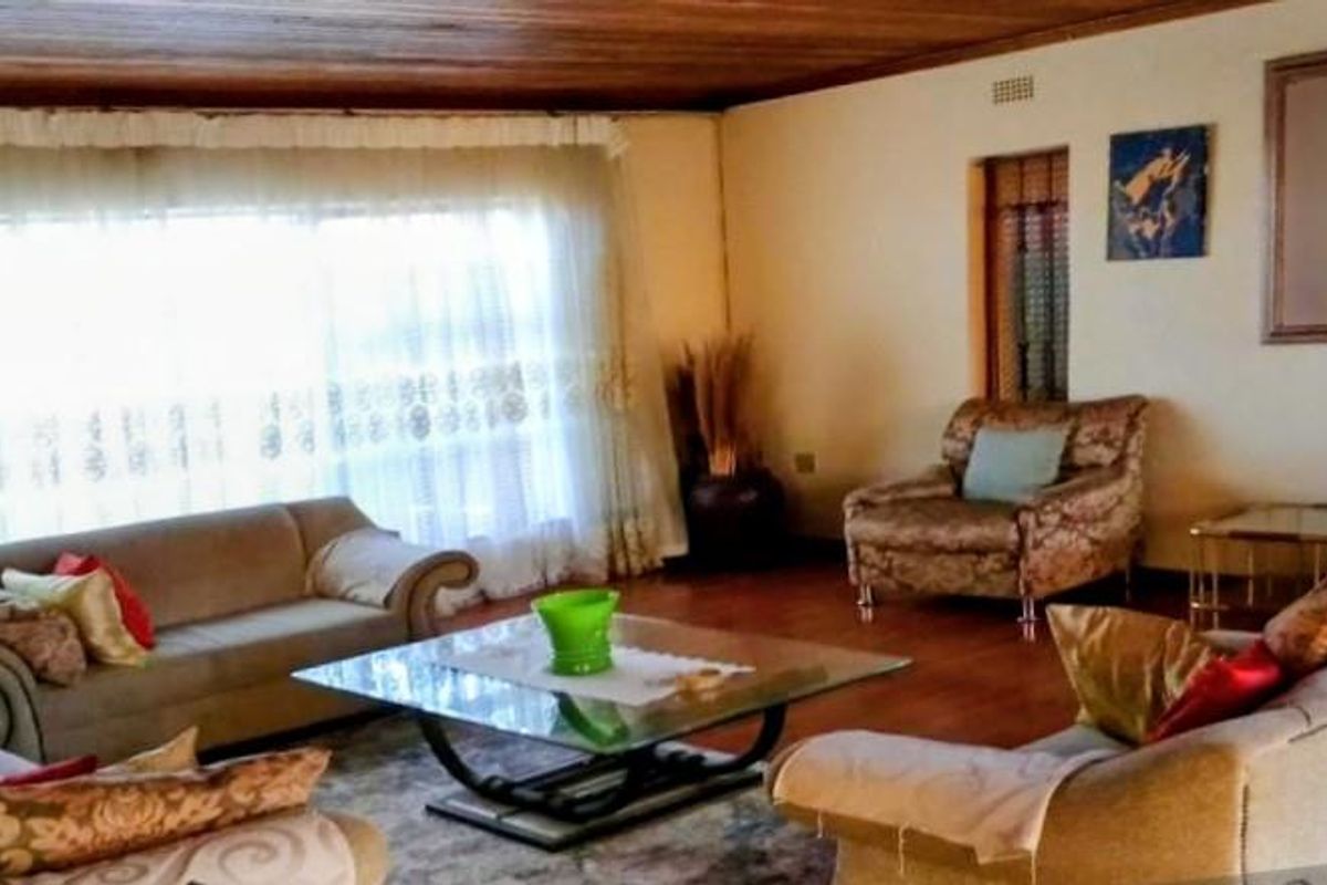 A spacious living room featuring a timber-paneled ceiling, large windows with natural light, and neutral wall finishes.