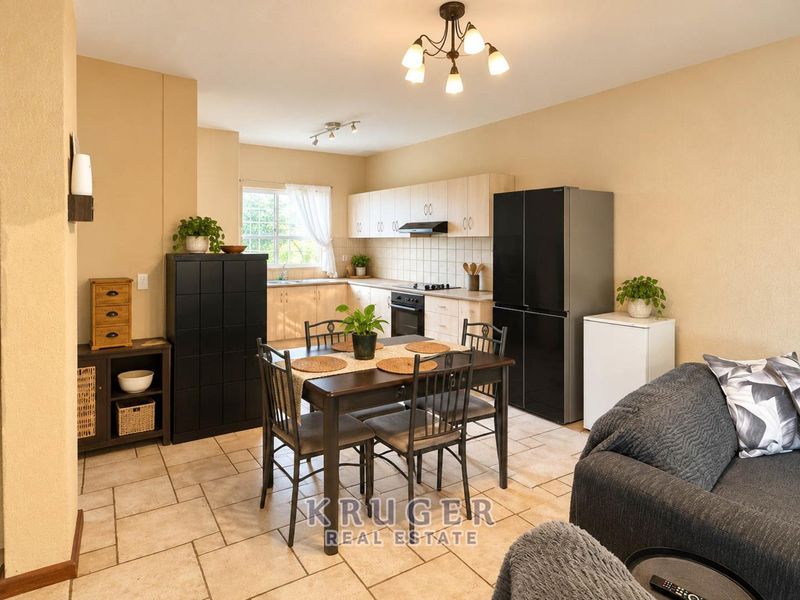 Open-plan kitchen and dining area featuring light wood cabinetry, tiled flooring, and a functional layout with integrated cooking appliances.