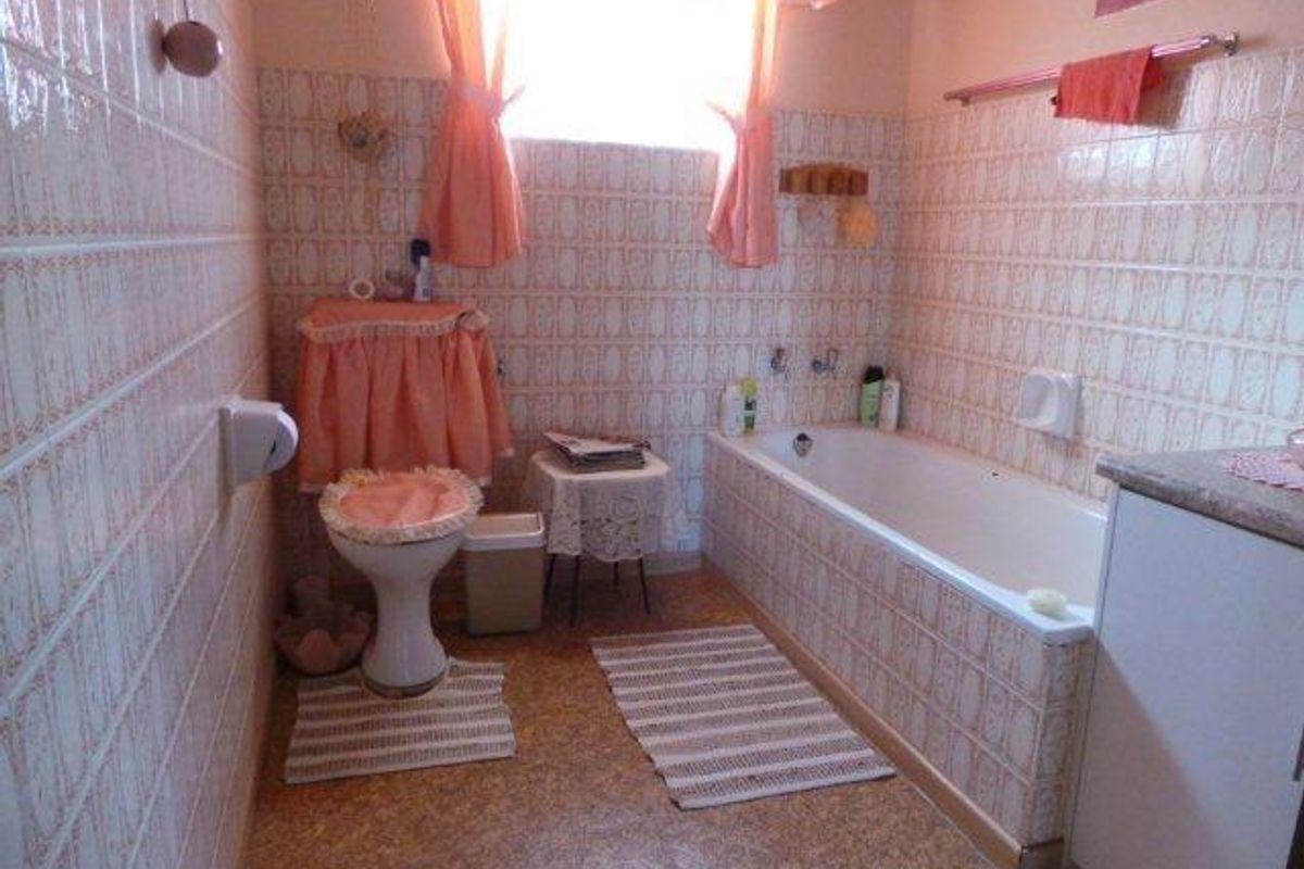A dated bathroom featuring original wall tiles, a standard bathtub, and a toilet, offering significant potential for a modern renovation.