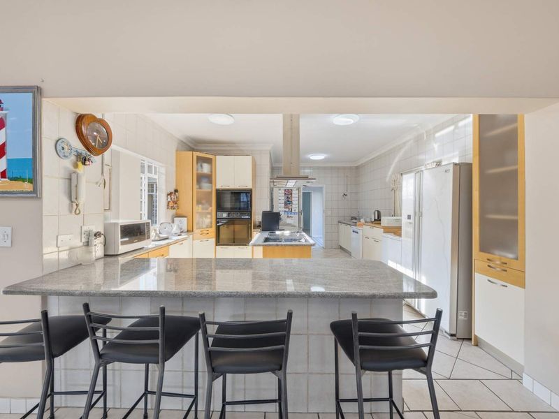Spacious kitchen featuring a granite breakfast bar, built-in oven, microwave, and ample cabinetry, offering a functional layout with tiled finishes throughout.