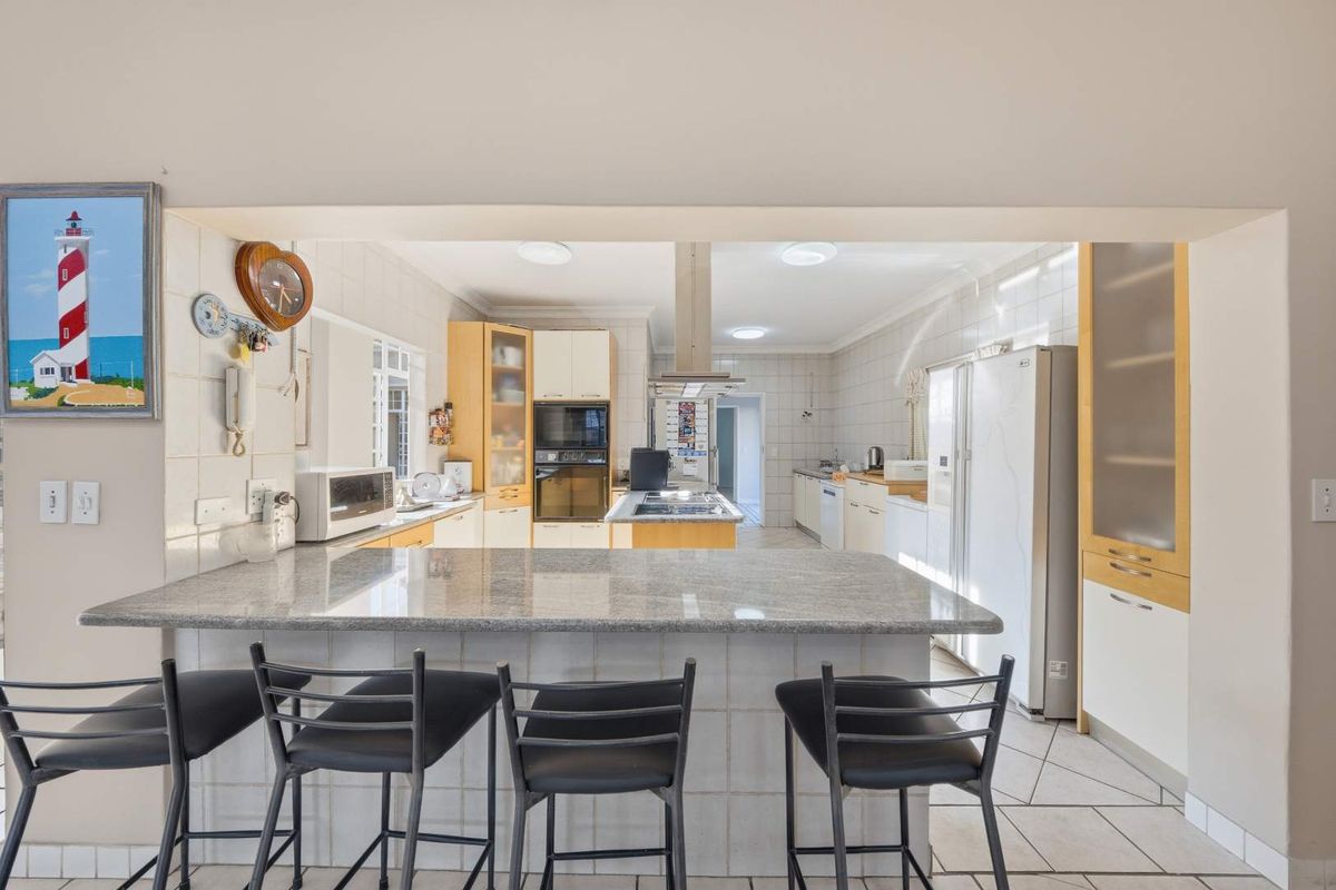 Spacious kitchen featuring a granite breakfast bar, built-in oven, microwave, and ample cabinetry, offering a functional layout with tiled finishes throughout.