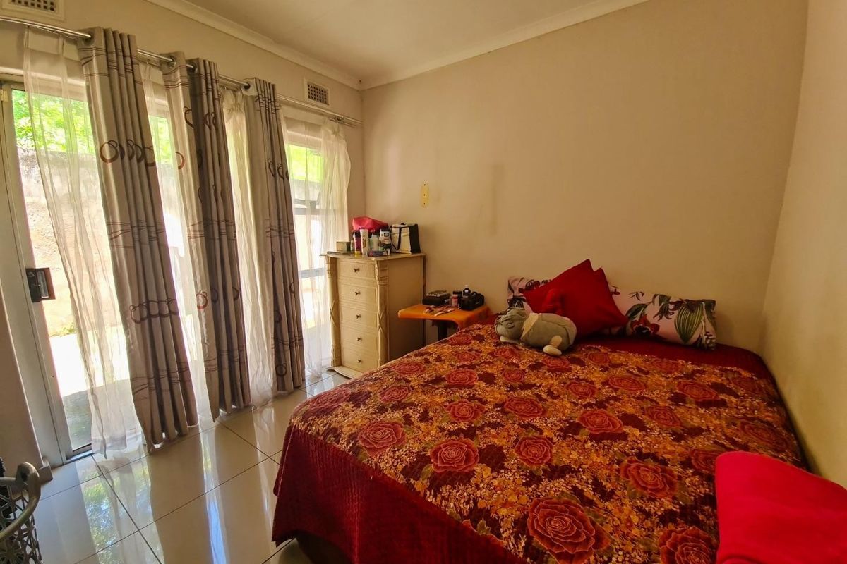 A bedroom featuring tiled flooring and a large sliding glass door providing access to the exterior.