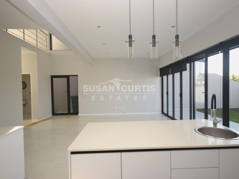 Spacious open-plan living area featuring a modern kitchen island, sleek cabinetry, and large sliding glass doors that open to the garden.
