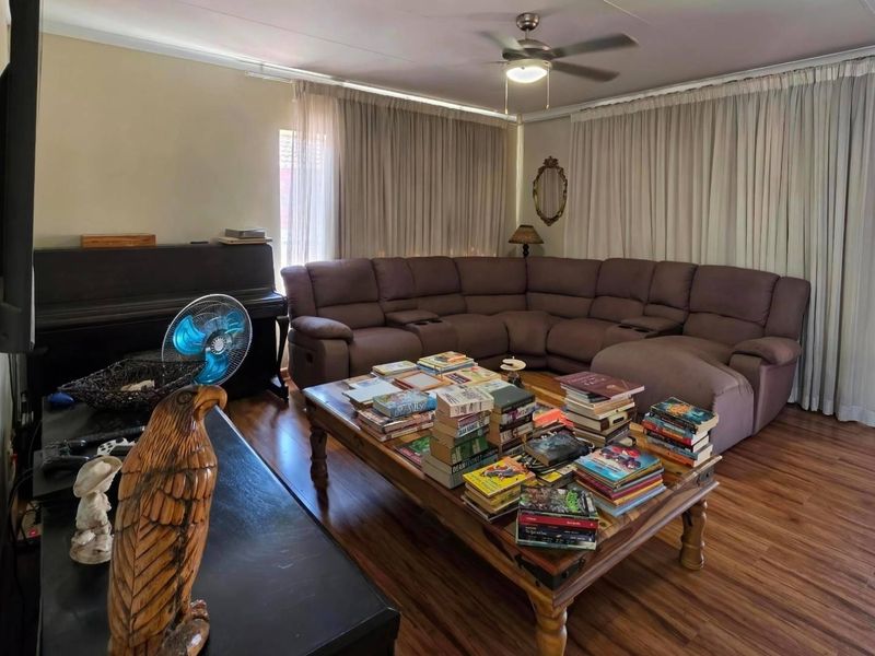 A spacious living room featuring laminate flooring and a ceiling fan, offering a comfortable area for relaxation and family gatherings.