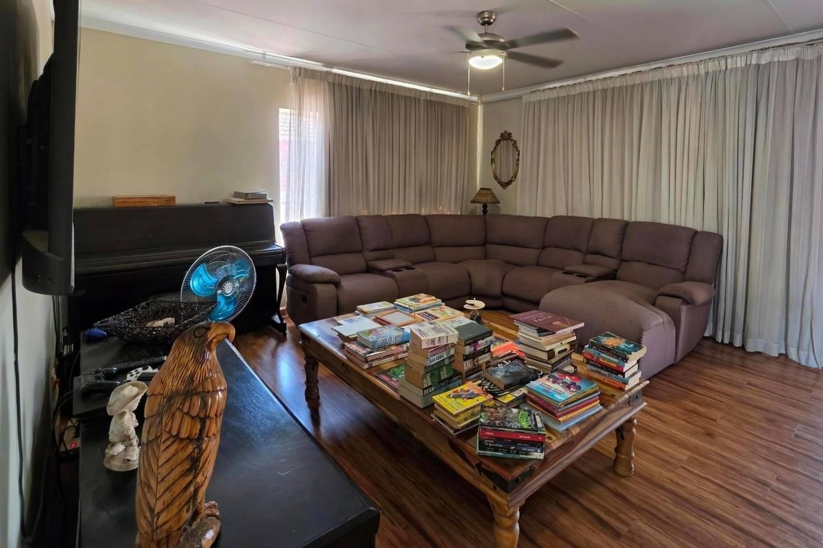 A spacious living room featuring laminate flooring and a ceiling fan, offering a comfortable area for relaxation and family gatherings.