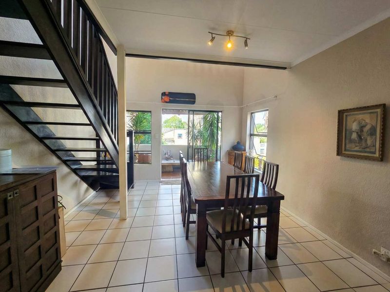 Dining area featuring tiled flooring, a staircase, and access to an outdoor patio through a sliding glass door.