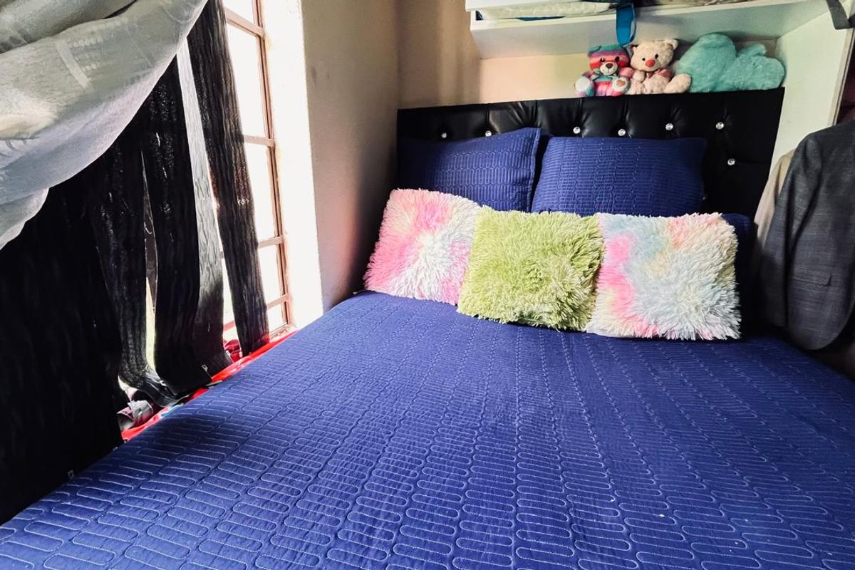 A compact bedroom featuring a window with natural light and a built-in shelf above the bed area.