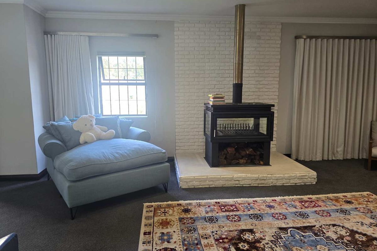 A cozy living room featuring a prominent white brick fireplace with a modern wood-burning stove and a raised hearth.
