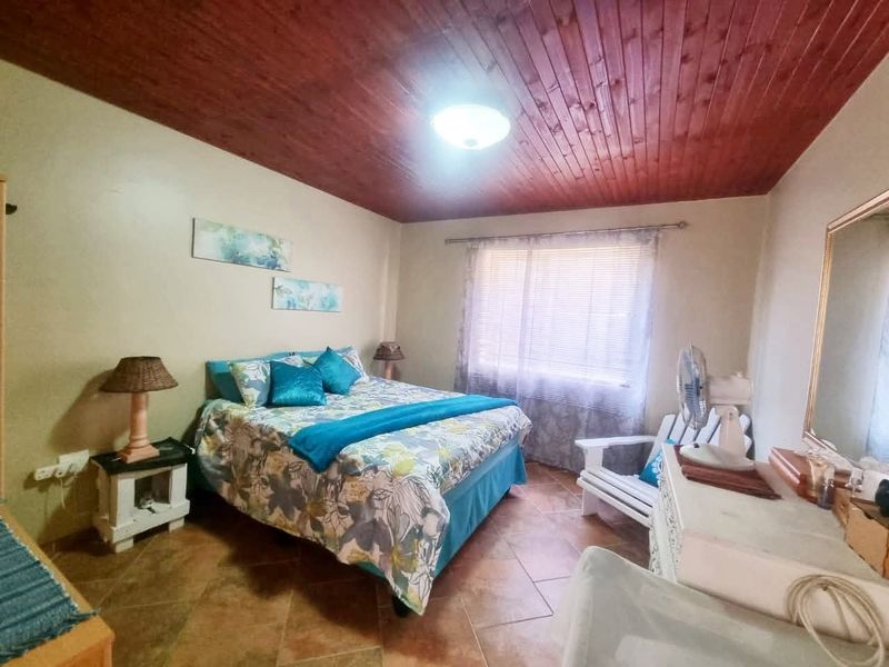 A bedroom featuring a warm timber tongue and groove ceiling, ceramic tiled flooring, and a large wall-mounted mirror.