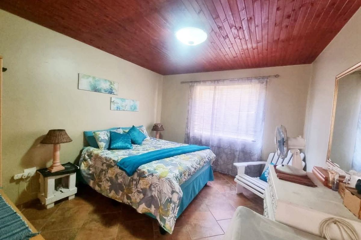 A bedroom featuring a warm timber tongue and groove ceiling, ceramic tiled flooring, and a large wall-mounted mirror.