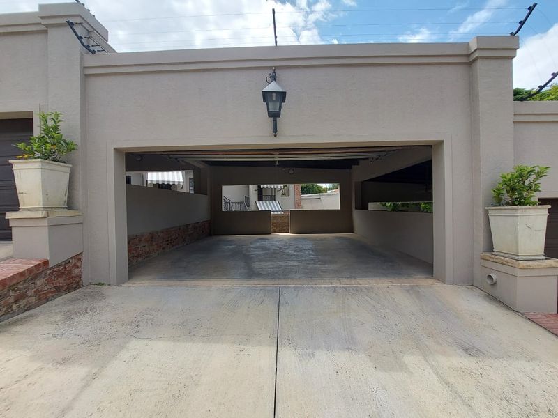 A spacious open-plan garage area featuring concrete flooring, brickwork detailing, and an exterior wall-mounted light fixture.