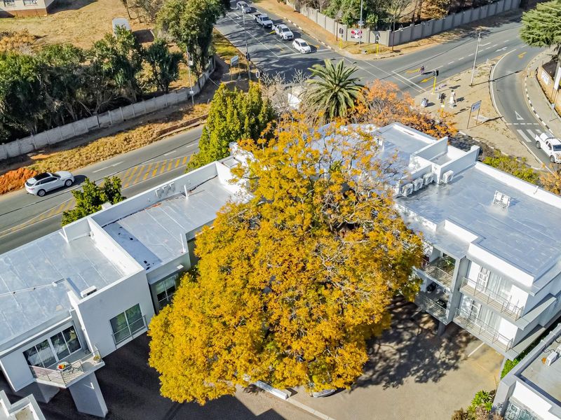 Aerial view of the apartment complex showing the building layout, flat roof structure, external air conditioning units, and surrounding paved driveway and street access.