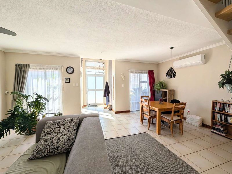Open-plan living and dining area featuring tiled flooring, split-system air conditioning, and direct access to outdoor spaces through sliding glass doors.