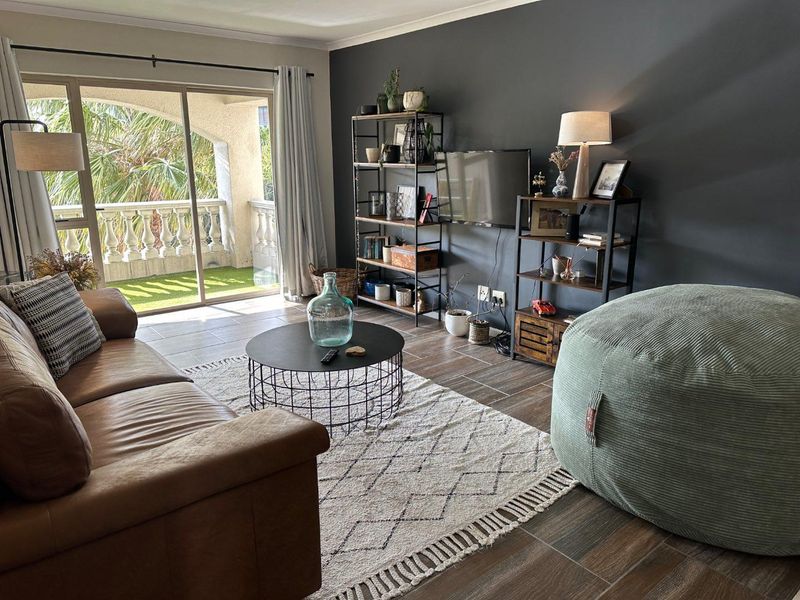 A well-lit living room featuring tiled flooring and a large sliding glass door providing direct access to a private balcony.