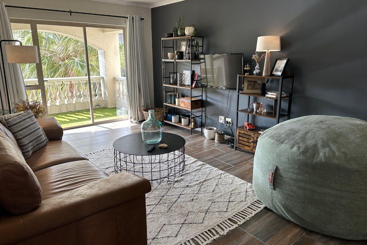 A well-lit living room featuring tiled flooring and a large sliding glass door providing direct access to a private balcony.