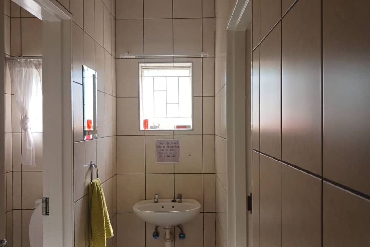 A functional bathroom featuring full-height wall tiling, a wall-mounted basin, and a small window for natural light.