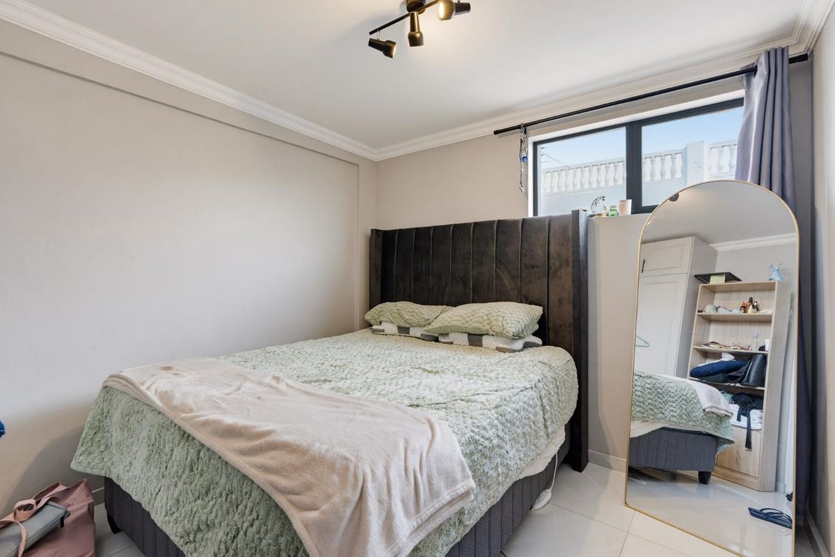 A well-maintained bedroom featuring tiled flooring, ceiling cornice, track lighting, and a built-in wardrobe, offering a clean and functional living space.