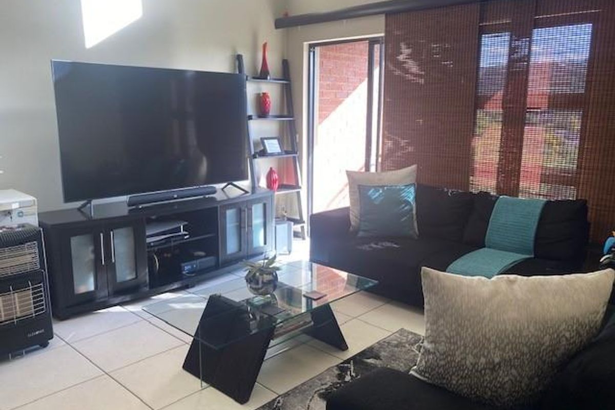 A bright living room featuring large format floor tiles and sliding glass doors leading to an outdoor area.