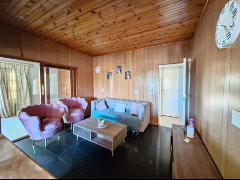 Living room featuring warm timber wall paneling and ceiling, tiled flooring, and a sliding glass door providing access to adjacent areas.