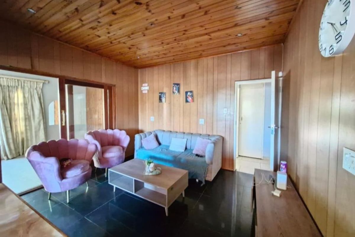 Living room featuring warm timber wall paneling and ceiling, tiled flooring, and a sliding glass door providing access to adjacent areas.