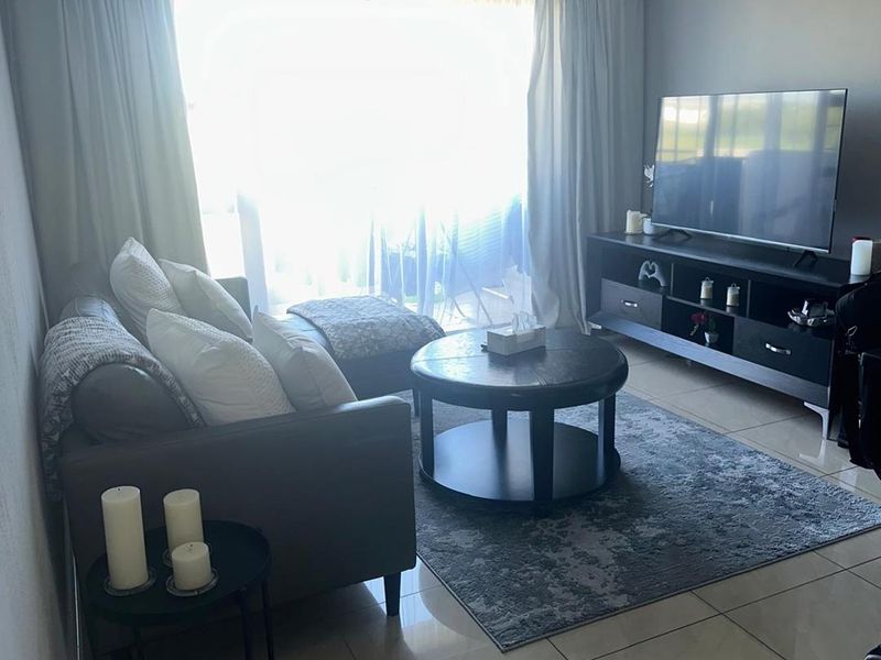 A comfortable living room featuring tiled flooring and a large sliding glass door that provides access to the outdoor area.