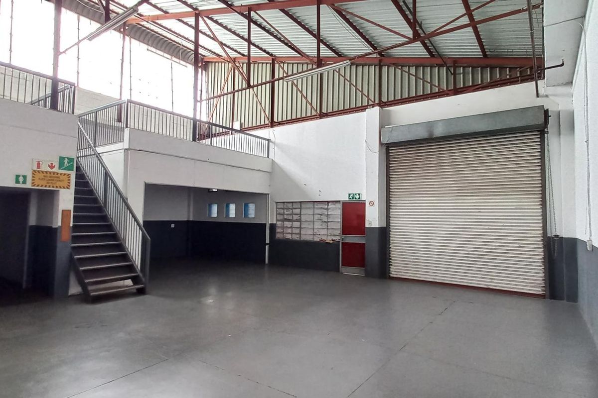 Spacious industrial warehouse unit featuring a high-clearance ceiling, roller shutter door access, and a functional mezzanine level suitable for office or storage use.