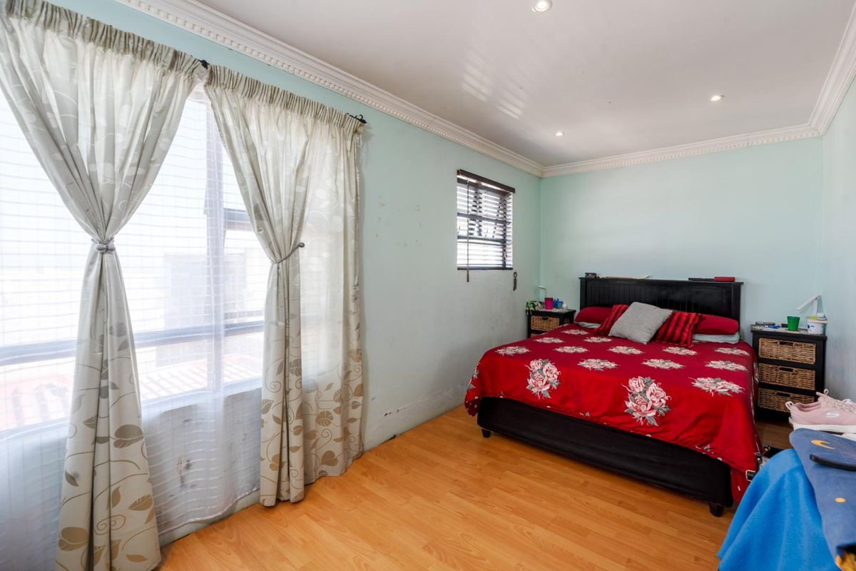 A bedroom featuring laminate flooring, crown molding, and recessed ceiling lighting, with natural light provided by two windows.