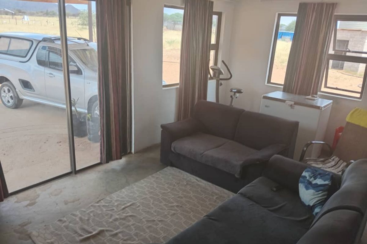 A living area featuring large sliding glass doors providing natural light and direct access to the exterior, with concrete flooring and neutral wall finishes.