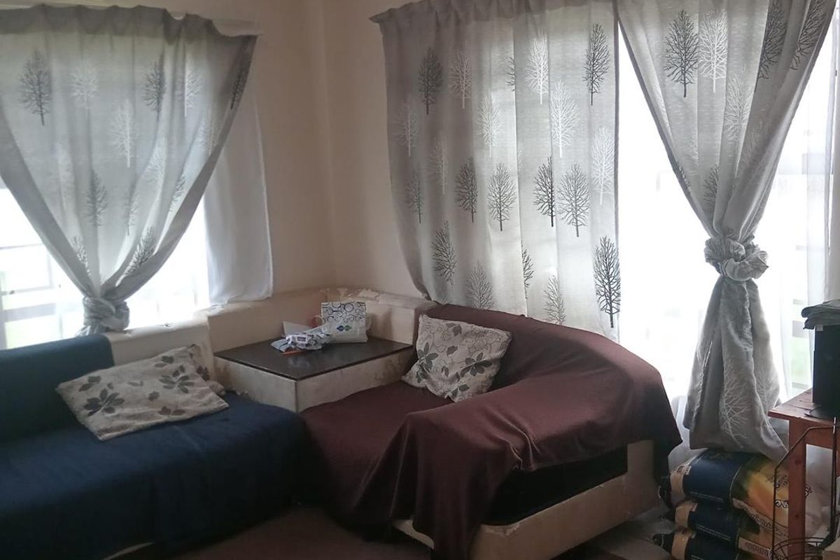 A living room area featuring large windows with curtains and built-in ventilation grilles.