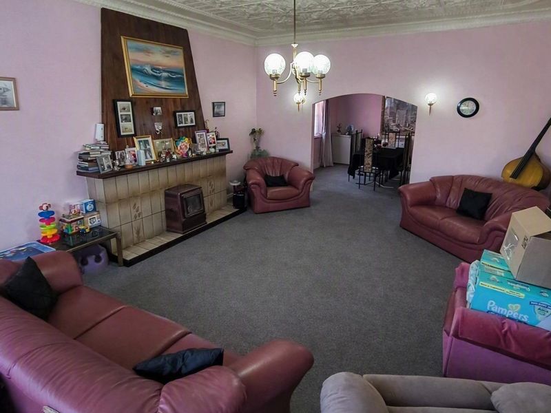 Spacious living room featuring a traditional fireplace with tiled surround, decorative ceiling details, and an arched opening leading to the dining area.