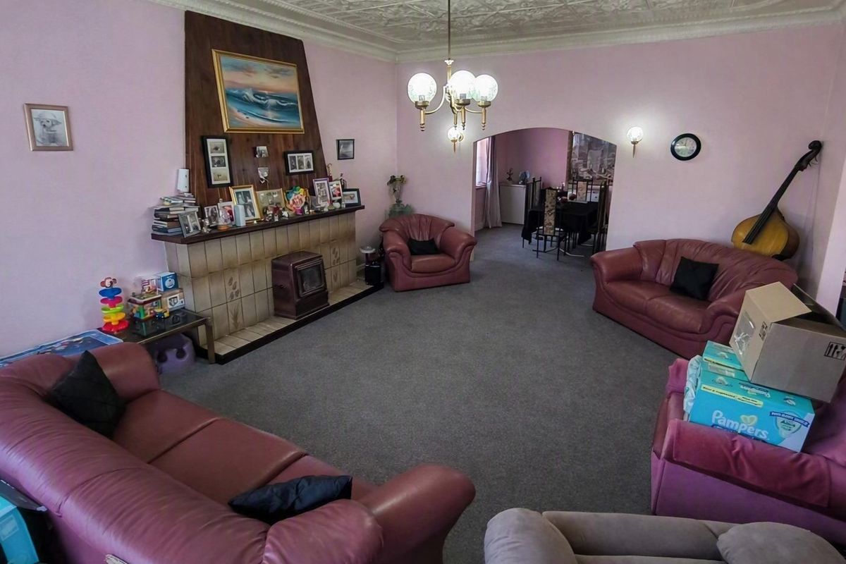 Spacious living room featuring a traditional fireplace with tiled surround, decorative ceiling details, and an arched opening leading to the dining area.