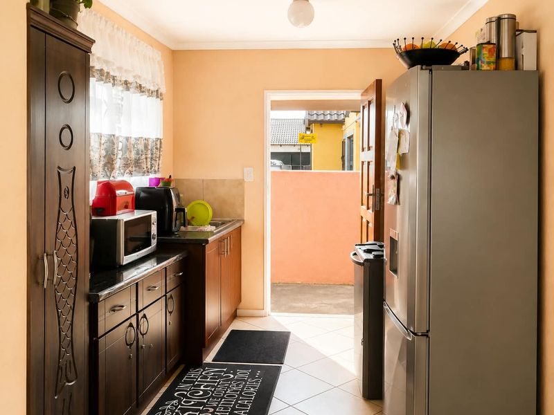A functional kitchen featuring dark wood cabinetry, granite countertops, and tiled flooring, with direct access to an outdoor area.