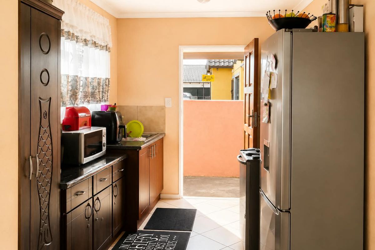A functional kitchen featuring dark wood cabinetry, granite countertops, and tiled flooring, with direct access to an outdoor area.