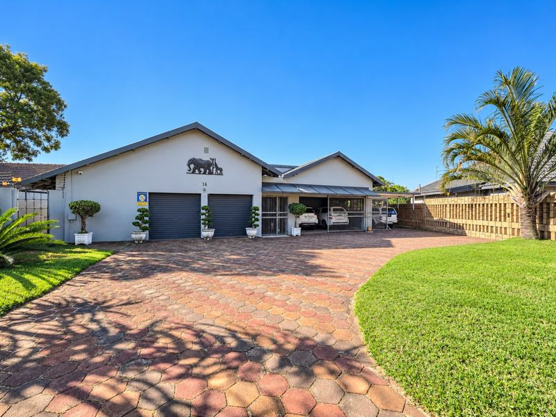 Front view of the property featuring a paved driveway, double garage, and a covered carport area with secure gated access.