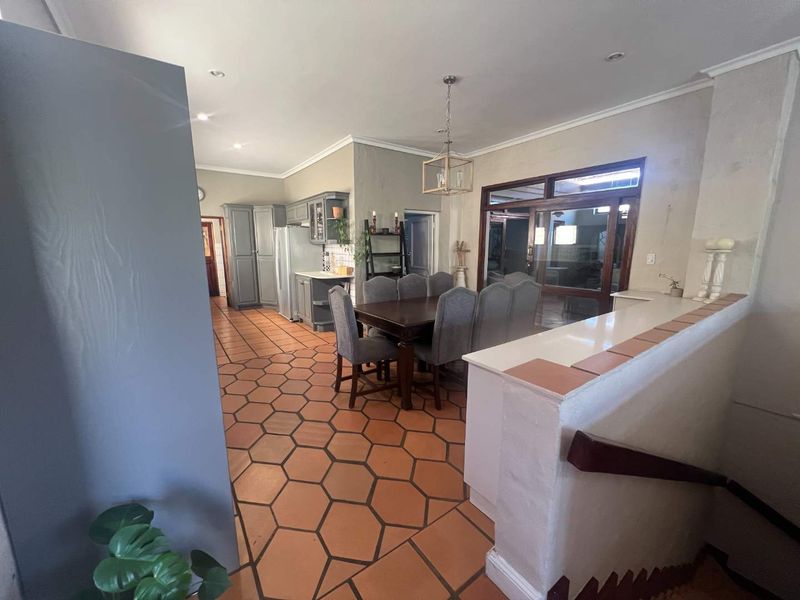 Open-plan living and dining area featuring distinctive hexagonal terracotta floor tiles, recessed lighting, and direct access to an adjoining patio through timber-framed glass doors.
