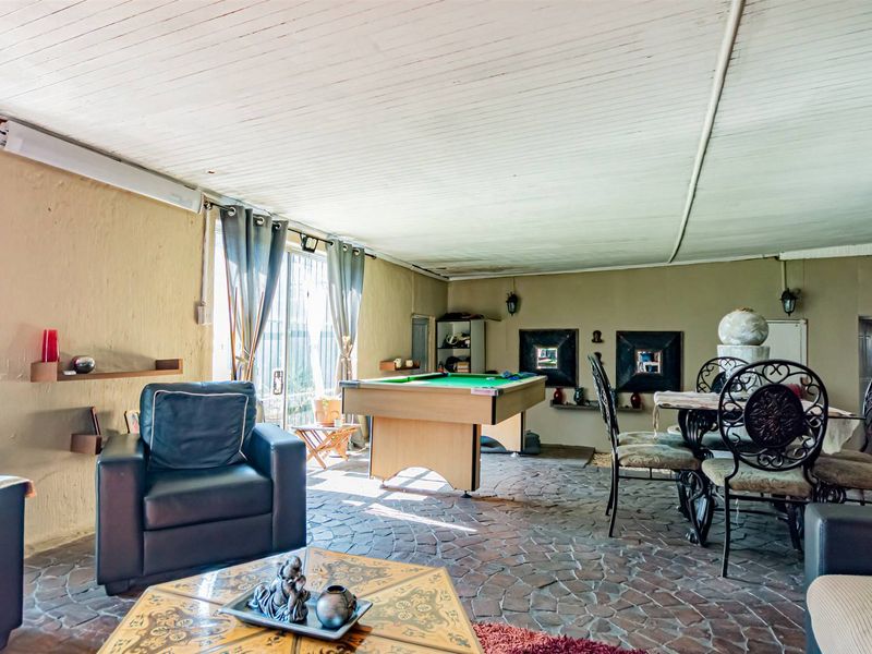 Spacious living area featuring unique stone flooring and a timber-panelled ceiling, with direct access to the outdoors through sliding glass doors.