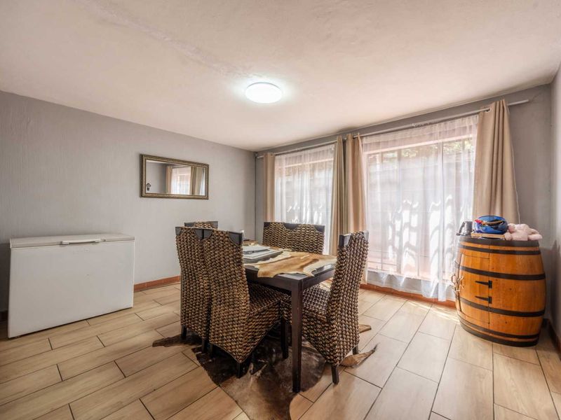 A dining room featuring tiled flooring and large windows that provide natural light, creating a functional space for family meals.