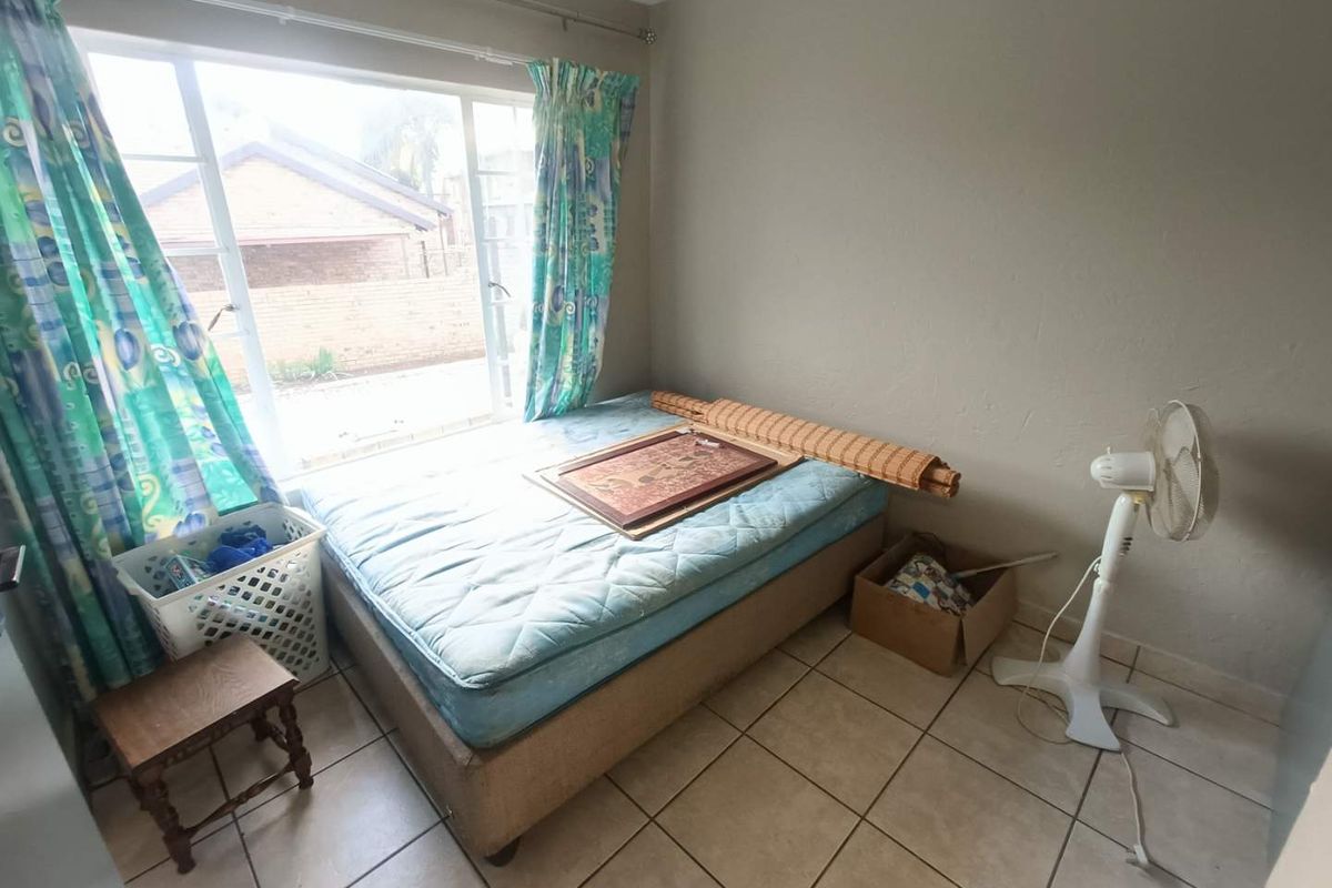 A bedroom featuring tiled flooring and a large window providing natural light, suitable for a comfortable living space.