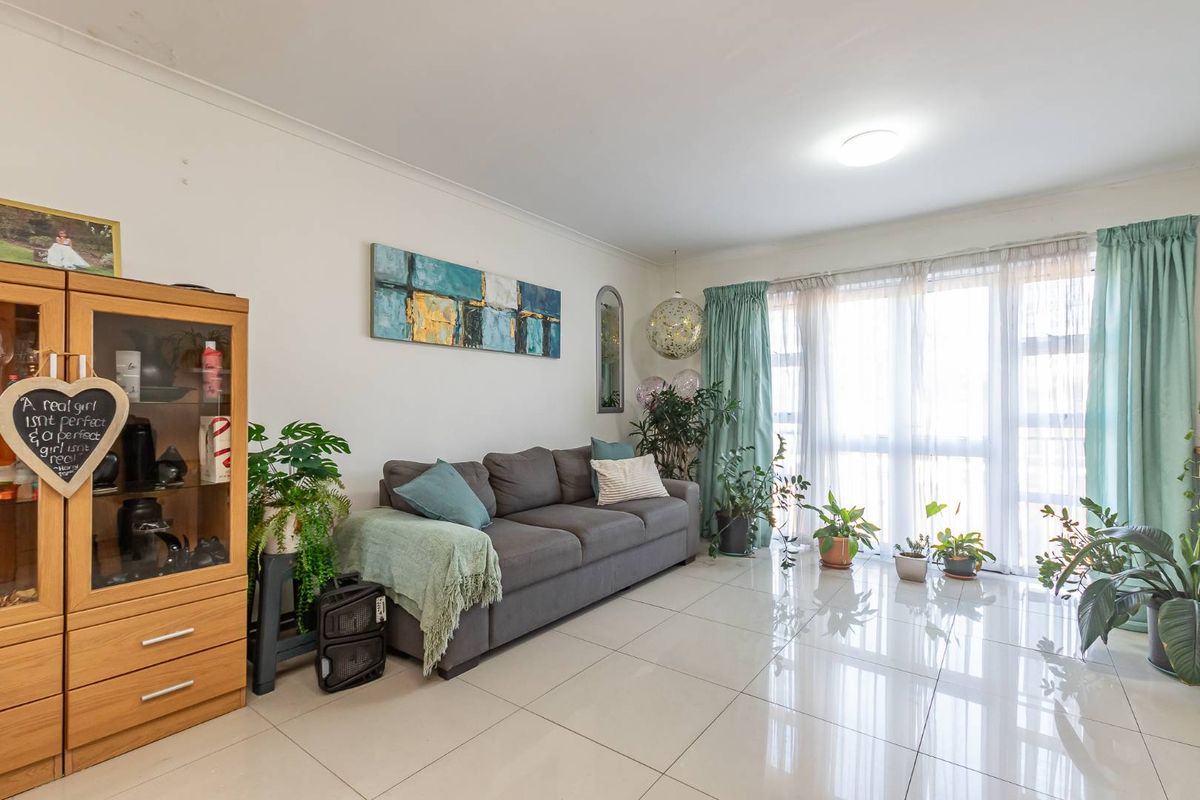 A bright living room featuring large sliding glass doors that provide ample natural light and polished tiled flooring throughout the space.