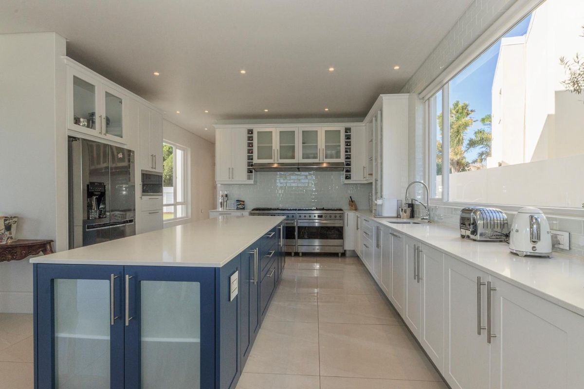 Modern, spacious kitchen featuring a large central island, quartz countertops, high-end stainless steel appliances, and ample built-in cabinetry with a clean, contemporary finish.