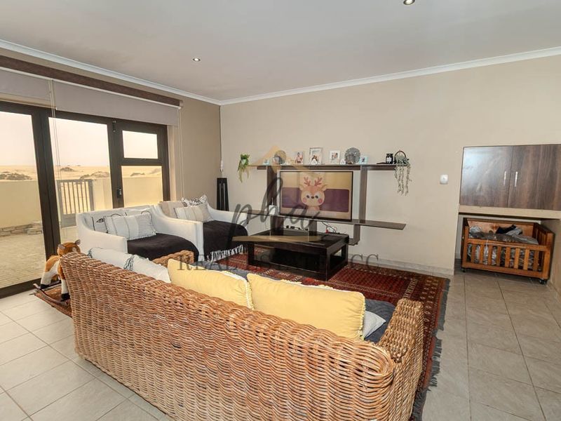 Spacious living room featuring tiled flooring, recessed lighting, and large sliding glass doors that provide access to an outdoor area.