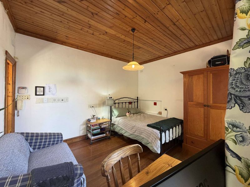 A bedroom featuring timber tongue and groove ceiling paneling and timber flooring, providing a rustic aesthetic.