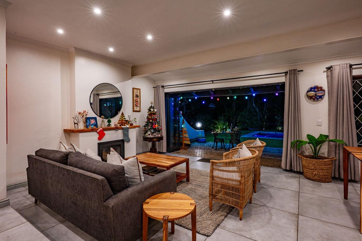 Spacious living room featuring a built-in fireplace and large folding doors that open onto a covered patio with pool access.