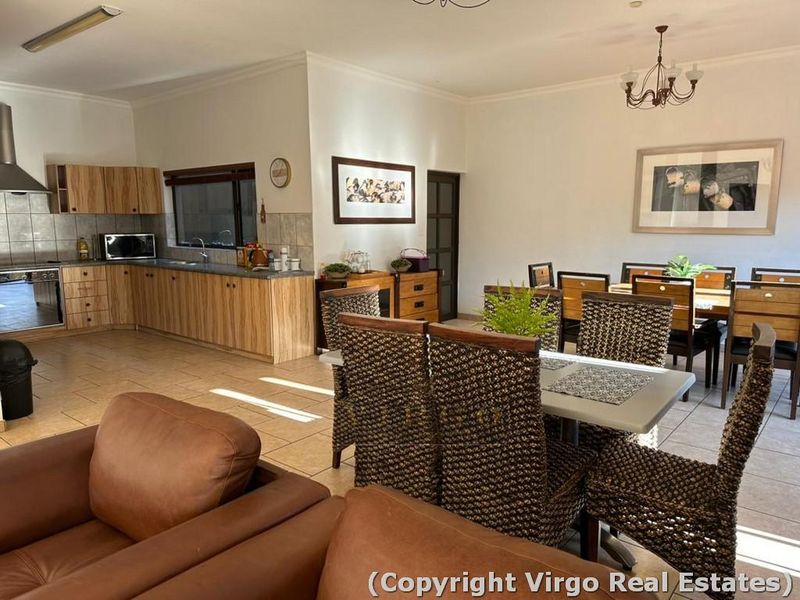 Open-plan living and dining area featuring a functional kitchen with built-in cabinetry, tiled flooring, and integrated appliances.