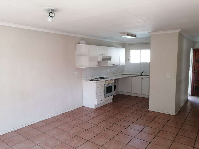 A functional, empty kitchen featuring white built-in cabinetry, an integrated stove and oven, tiled flooring, and a tiled backsplash.
