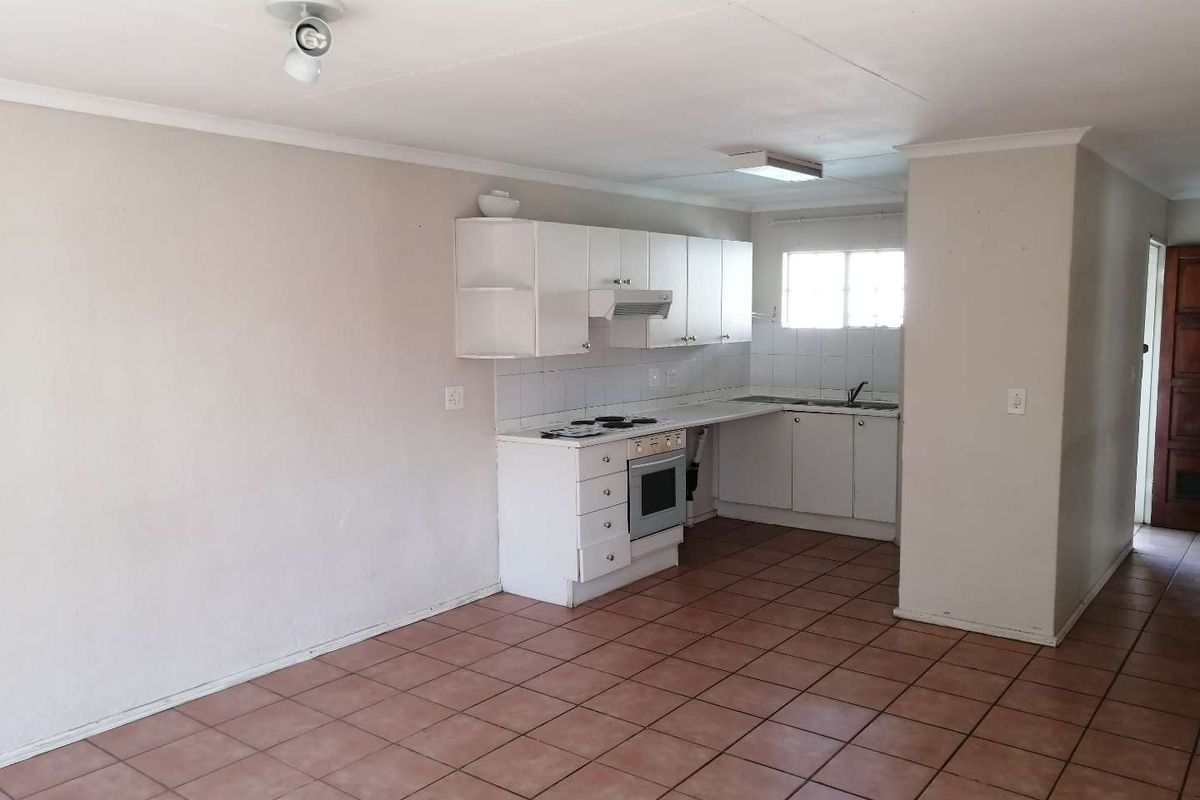 A functional, empty kitchen featuring white built-in cabinetry, an integrated stove and oven, tiled flooring, and a tiled backsplash.