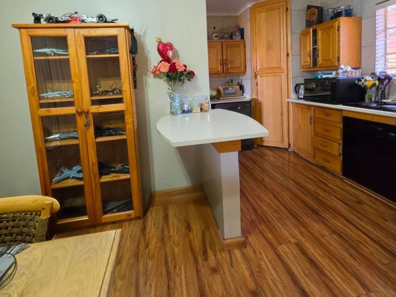 A functional kitchen featuring wooden cabinetry, laminate flooring, and a built-in breakfast bar, offering a practical layout for daily meal preparation.