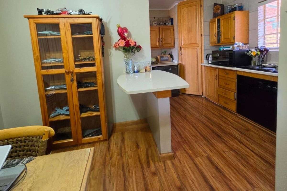 A functional kitchen featuring wooden cabinetry, laminate flooring, and a built-in breakfast bar, offering a practical layout for daily meal preparation.